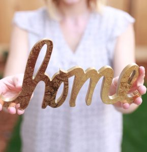 woman holding home sign
